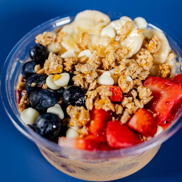 A vibrant acai bowl with blueberries, strawberries, bananas, granola, and white chocolate chips.